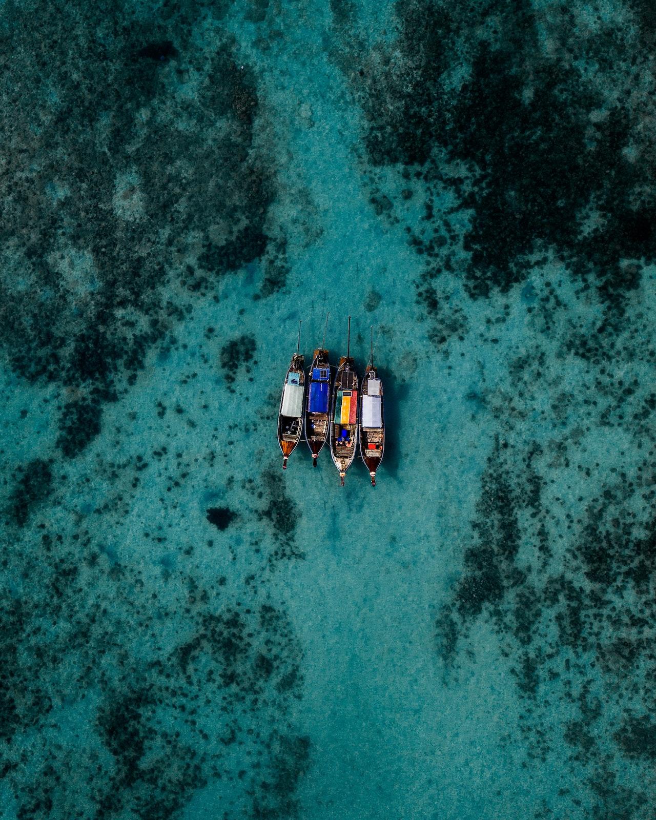 Bovenaanzicht van vier bootjes op de Andamanse zee bij de eilanden van Koh Phi Phi